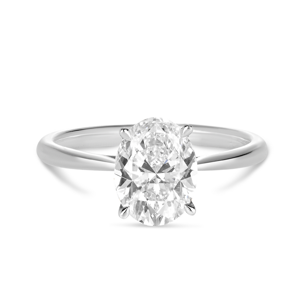 white gold engagement ring with tapered band and an oval cut diamond in a petite and delicate setting